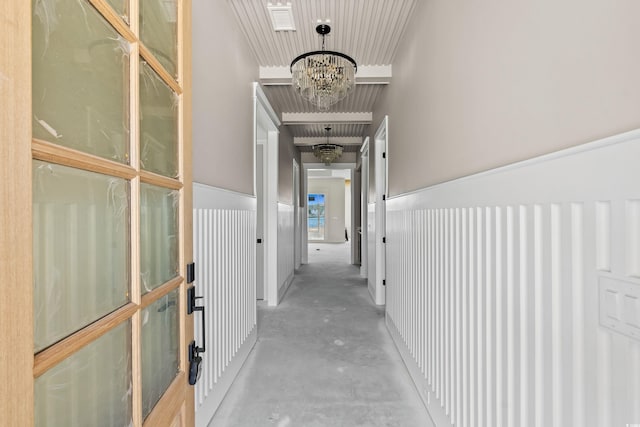 hallway with concrete flooring and a notable chandelier