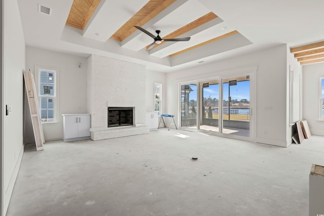 unfurnished living room featuring a brick fireplace, a raised ceiling, visible vents, and concrete floors