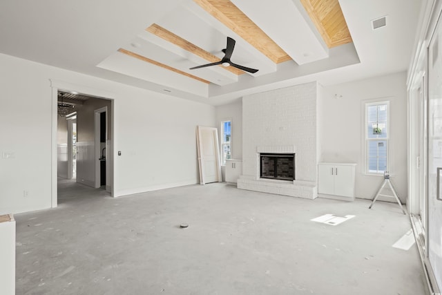 unfurnished living room with a brick fireplace, a raised ceiling, visible vents, and unfinished concrete floors