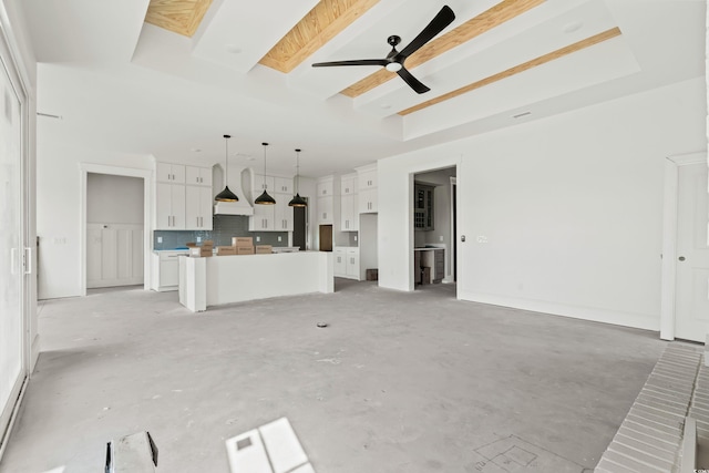 unfurnished living room featuring a skylight, ceiling fan, a tray ceiling, and unfinished concrete floors