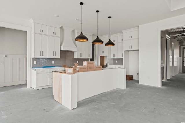 kitchen with decorative backsplash, unfinished concrete flooring, a center island, premium range hood, and white cabinetry