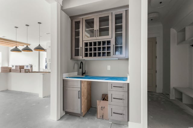 kitchen featuring gray cabinetry, concrete floors, light countertops, glass insert cabinets, and pendant lighting