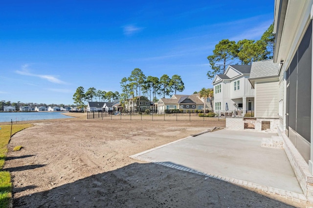 view of yard with a water view, a patio area, a residential view, and fence