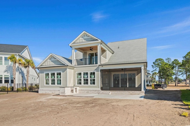 rear view of house with a ceiling fan, a sunroom, fence, a balcony, and driveway