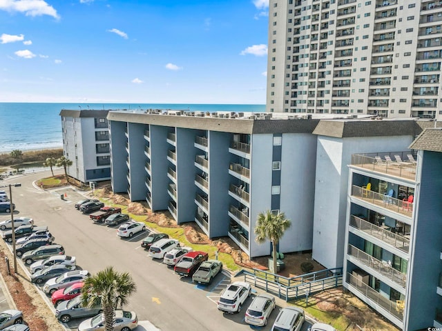 view of building exterior featuring uncovered parking and a water view