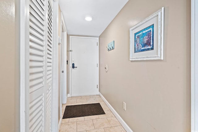 doorway with light tile patterned floors and baseboards