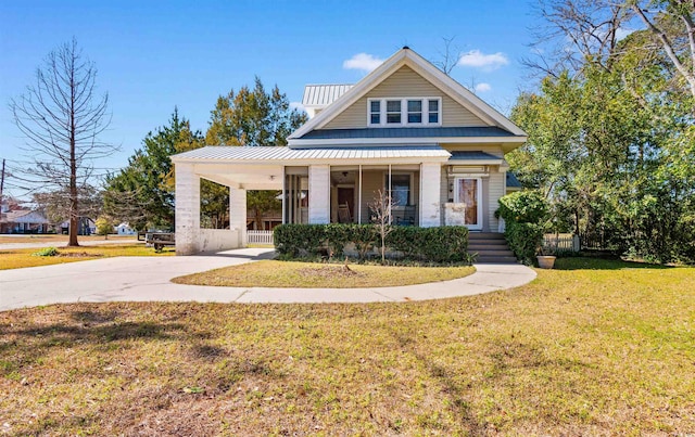 view of front facade with covered porch, driveway, a front lawn, and metal roof