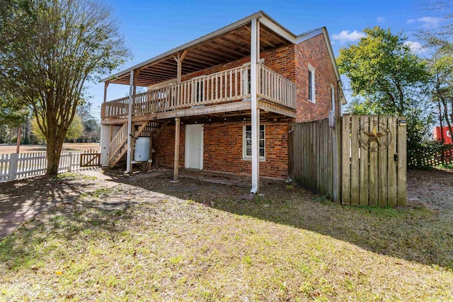 back of property featuring a deck, brick siding, stairway, and fence