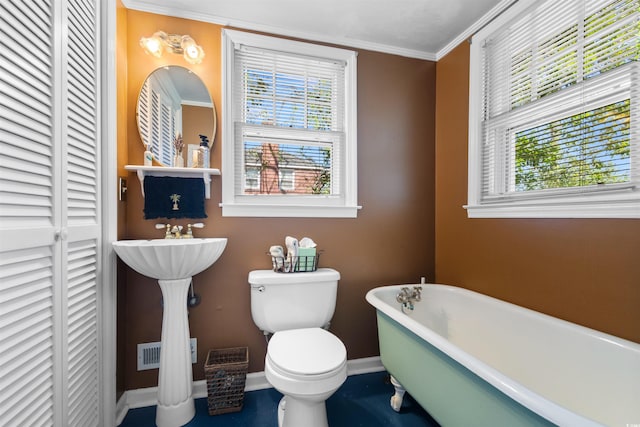 full bathroom featuring crown molding, a closet, toilet, a freestanding tub, and baseboards