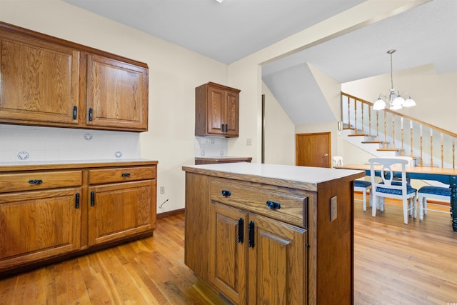 kitchen with light wood-style floors, a chandelier, brown cabinets, and pendant lighting