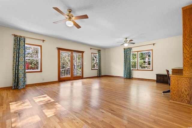 unfurnished living room with light wood-type flooring, a healthy amount of sunlight, and a textured ceiling