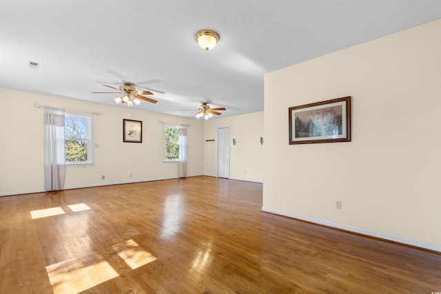 unfurnished room featuring a textured ceiling, wood finished floors, visible vents, and baseboards