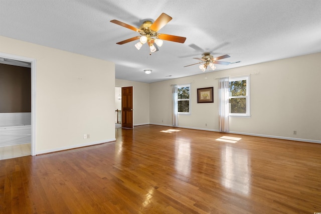 spare room with a textured ceiling, baseboards, and wood finished floors