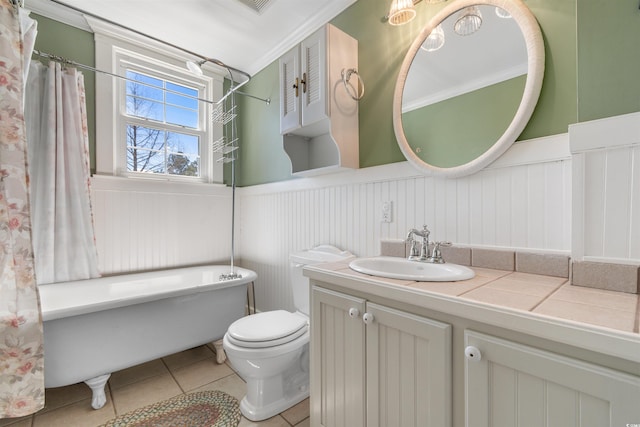 full bath featuring toilet, a wainscoted wall, a freestanding tub, and tile patterned floors