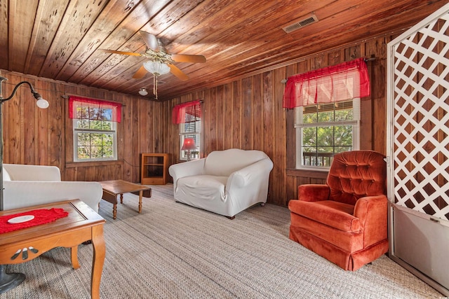 living area featuring a healthy amount of sunlight, wood ceiling, and wooden walls