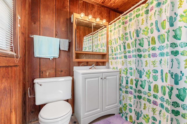 bathroom featuring curtained shower, wooden walls, toilet, and vanity