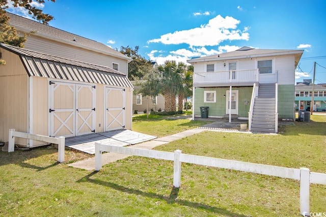 exterior space featuring an outbuilding, a storage shed, fence, a yard, and stairway