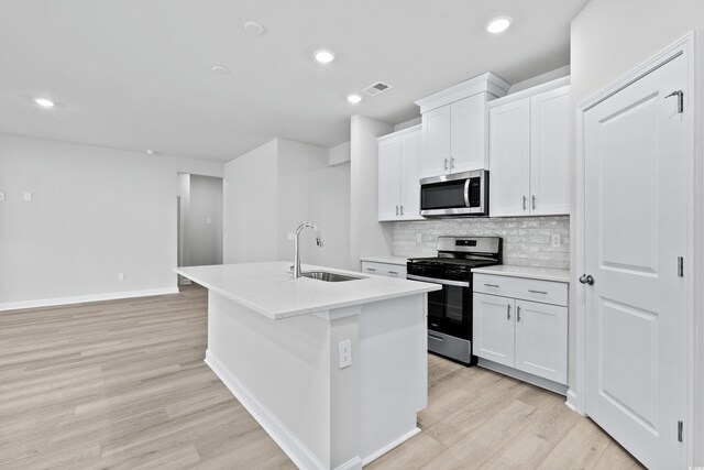 2104 Copper Creek Ct, Longs, SC 29568 - kitchen featuring light wood finished floors, an island with sink, a sink, stainless steel appliances, and tasteful backsplash