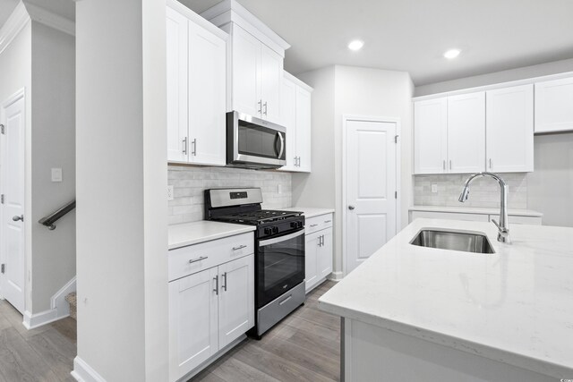 2104 Copper Creek Ct, Longs, SC 29568 - kitchen with light wood finished floors, white cabinets, stainless steel appliances, and a sink