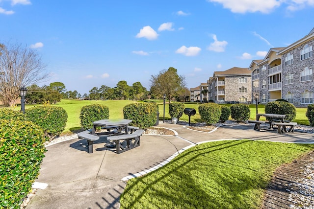 view of home's community featuring a patio area, a lawn, and a residential view