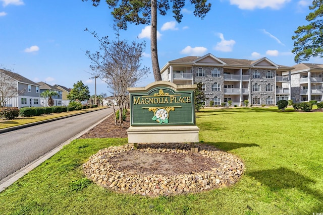 community sign featuring a residential view and a lawn