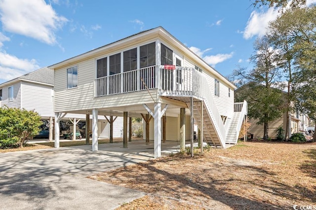 view of front of house featuring a sunroom, stairway, a carport, and concrete driveway