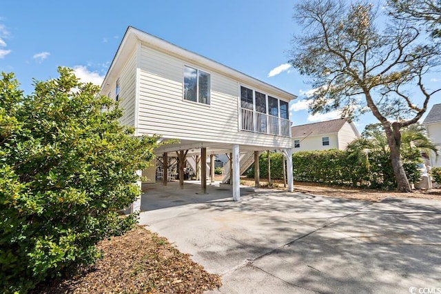 exterior space with a carport, concrete driveway, and stairway