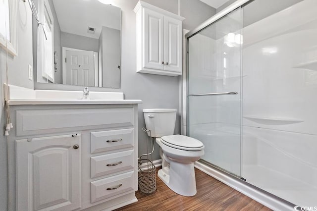 bathroom featuring a stall shower, vanity, toilet, and wood finished floors