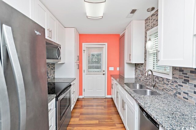 kitchen featuring visible vents, appliances with stainless steel finishes, white cabinets, a sink, and wood finished floors