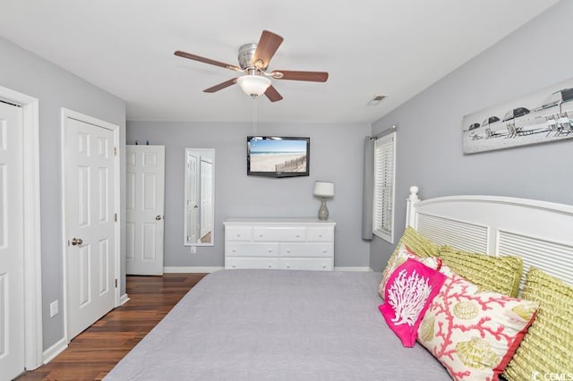 bedroom with ceiling fan, visible vents, baseboards, and dark wood-style flooring