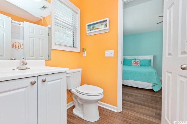 bathroom with baseboards, visible vents, toilet, wood finished floors, and vanity