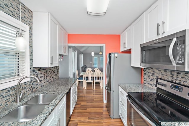 kitchen featuring tasteful backsplash, appliances with stainless steel finishes, light wood-type flooring, white cabinetry, and a sink