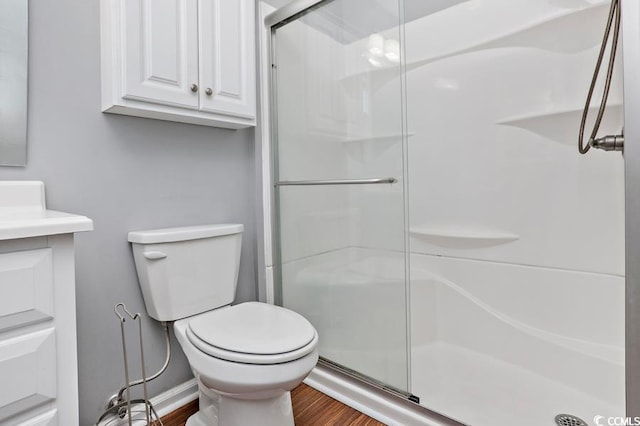 full bathroom with wood finished floors, a shower stall, and toilet