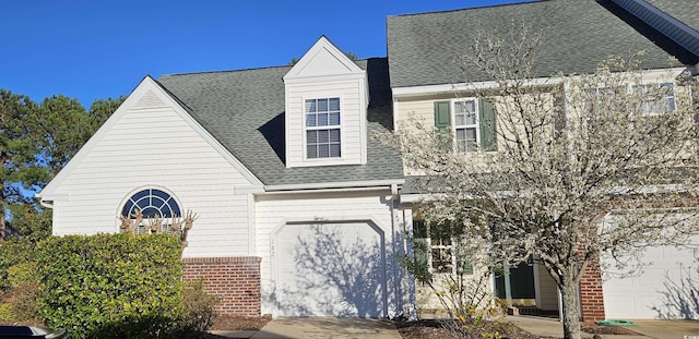 view of front facade featuring a shingled roof, an attached garage, and brick siding