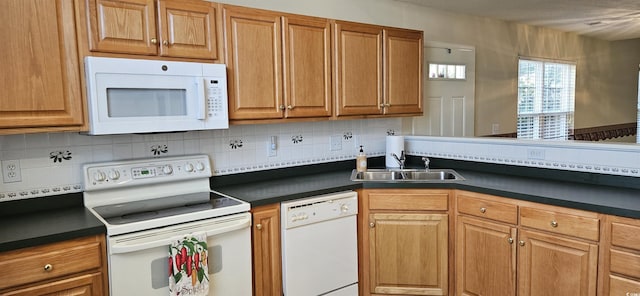 kitchen with white appliances, a sink, decorative backsplash, brown cabinetry, and dark countertops