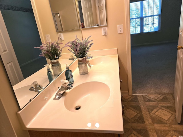 bathroom featuring double vanity, baseboards, and a sink