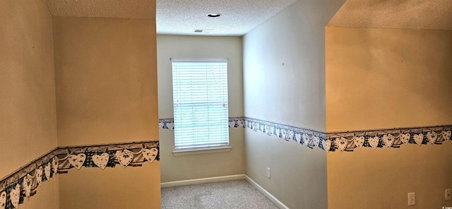 hall featuring visible vents, carpet flooring, a textured ceiling, and baseboards