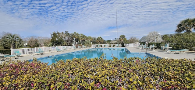 community pool with a patio area and fence