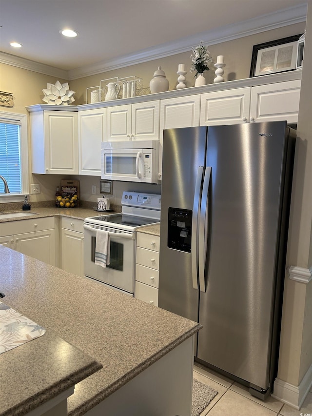 kitchen featuring white appliances, light tile patterned flooring, crown molding, and white cabinetry