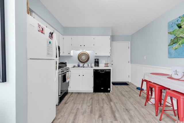 kitchen featuring freestanding refrigerator, light countertops, wainscoting, dishwasher, and gas range