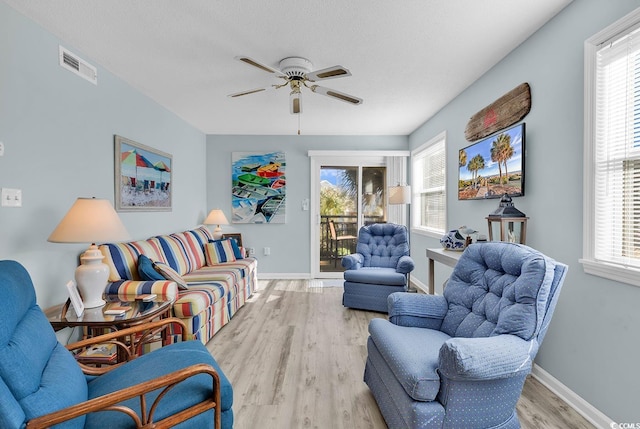 living area with visible vents, a healthy amount of sunlight, a ceiling fan, and wood finished floors