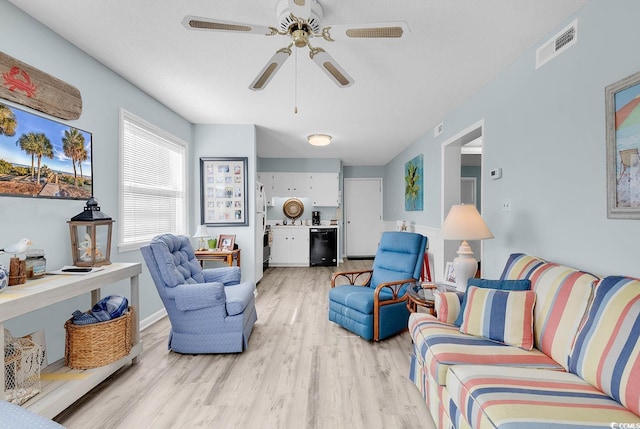 living room with light wood-type flooring, visible vents, and a ceiling fan