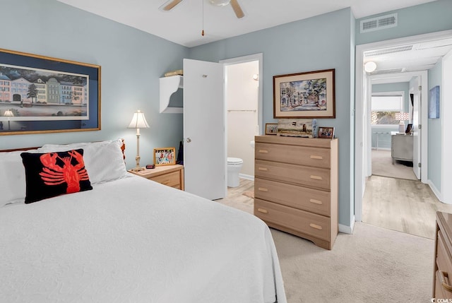 bedroom with a ceiling fan, baseboards, visible vents, ensuite bath, and light carpet