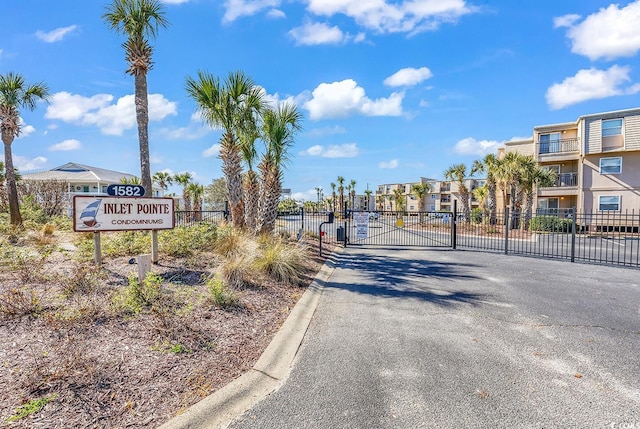 view of street featuring a gate, curbs, a residential view, and a gated entry