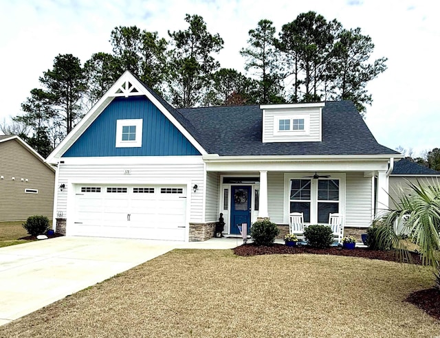 view of front facade featuring a shingled roof, covered porch, an attached garage, stone siding, and driveway