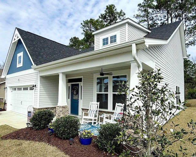 craftsman-style home featuring a shingled roof, concrete driveway, stone siding, ceiling fan, and a porch