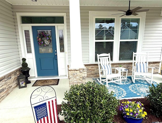 doorway to property with covered porch, ceiling fan, and stone siding