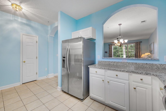 kitchen with light tile patterned floors, stainless steel refrigerator with ice dispenser, visible vents, and white cabinetry