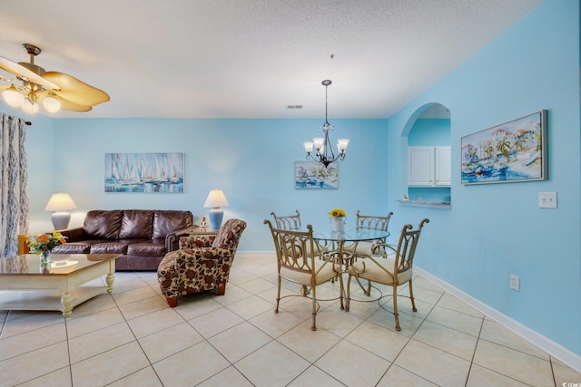 dining space featuring light tile patterned floors, a textured ceiling, ceiling fan with notable chandelier, visible vents, and baseboards