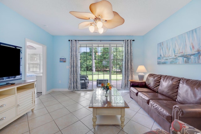 living area with light tile patterned floors, ceiling fan, and baseboards